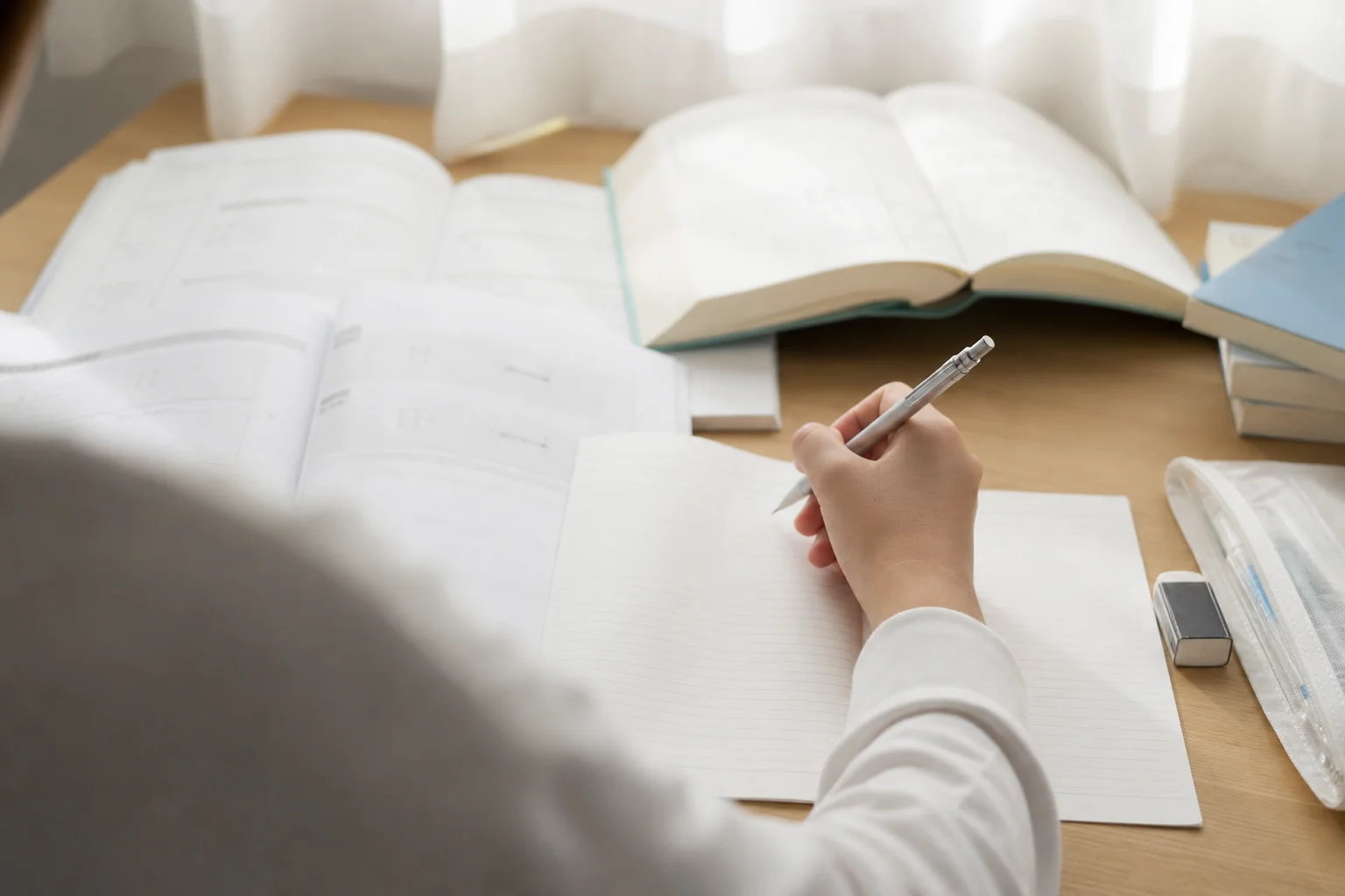 机に過去問や参考書を広げて、志望校の合格を目指して勉強している高校生の手元の様子